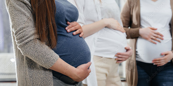 three pregnant women standing side by side